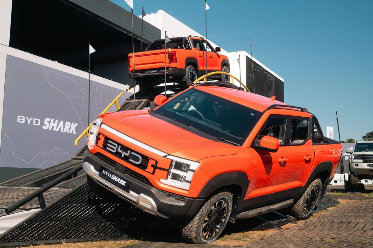 Duas picapes BYD Shark laranja em rampas de demonstração off-road no estande da marca em Goodwood
