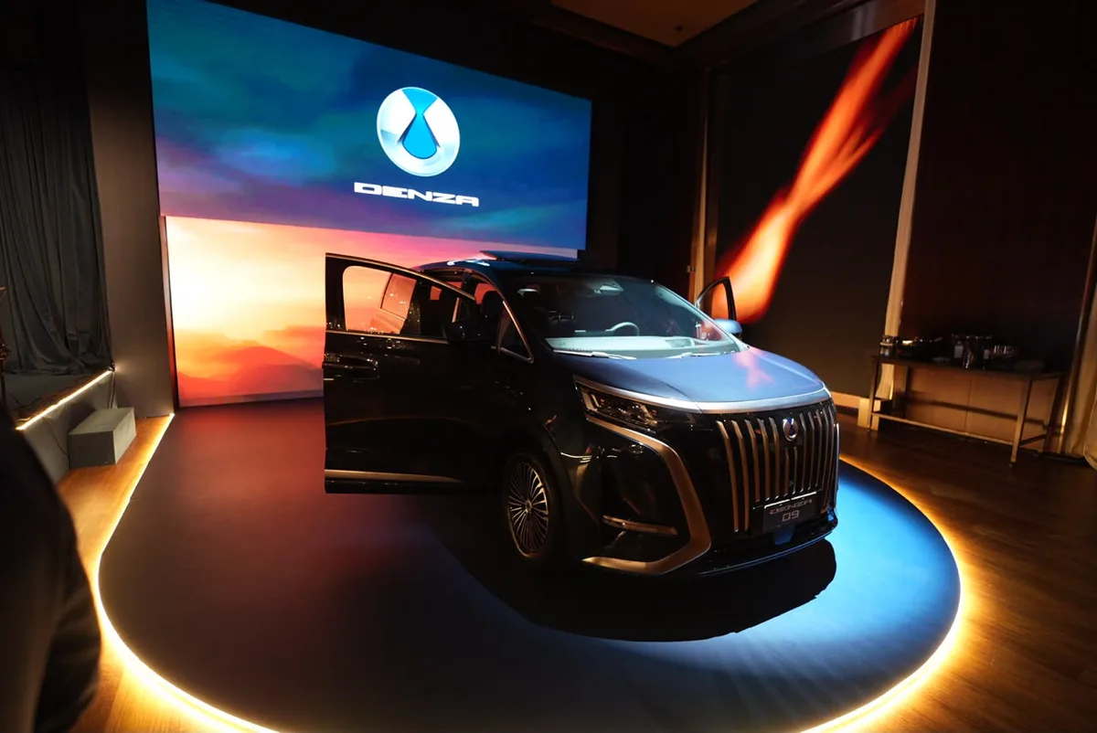 Minivan elétrica Denza D9 com porta lateral aberta, exposta em palco iluminado durante o evento