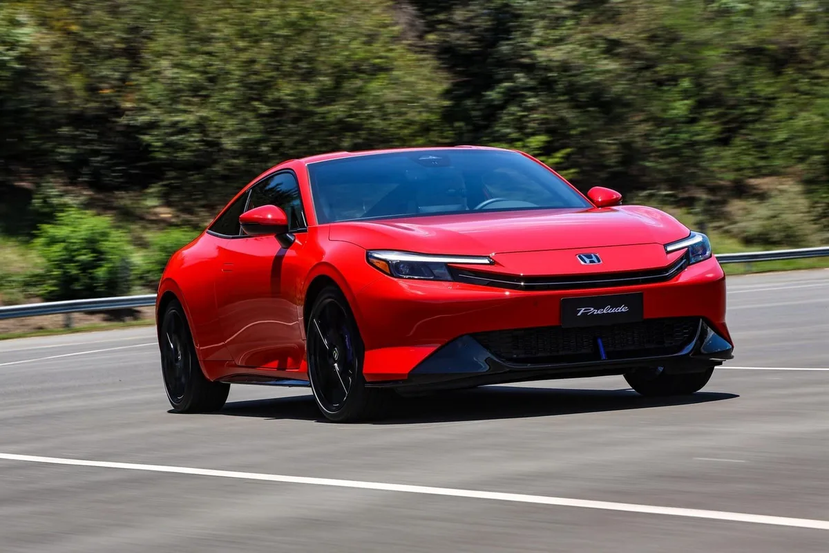 Honda Prelude e:HEV vermelho em movimento numa estrada, visto de três quartos dianteiro