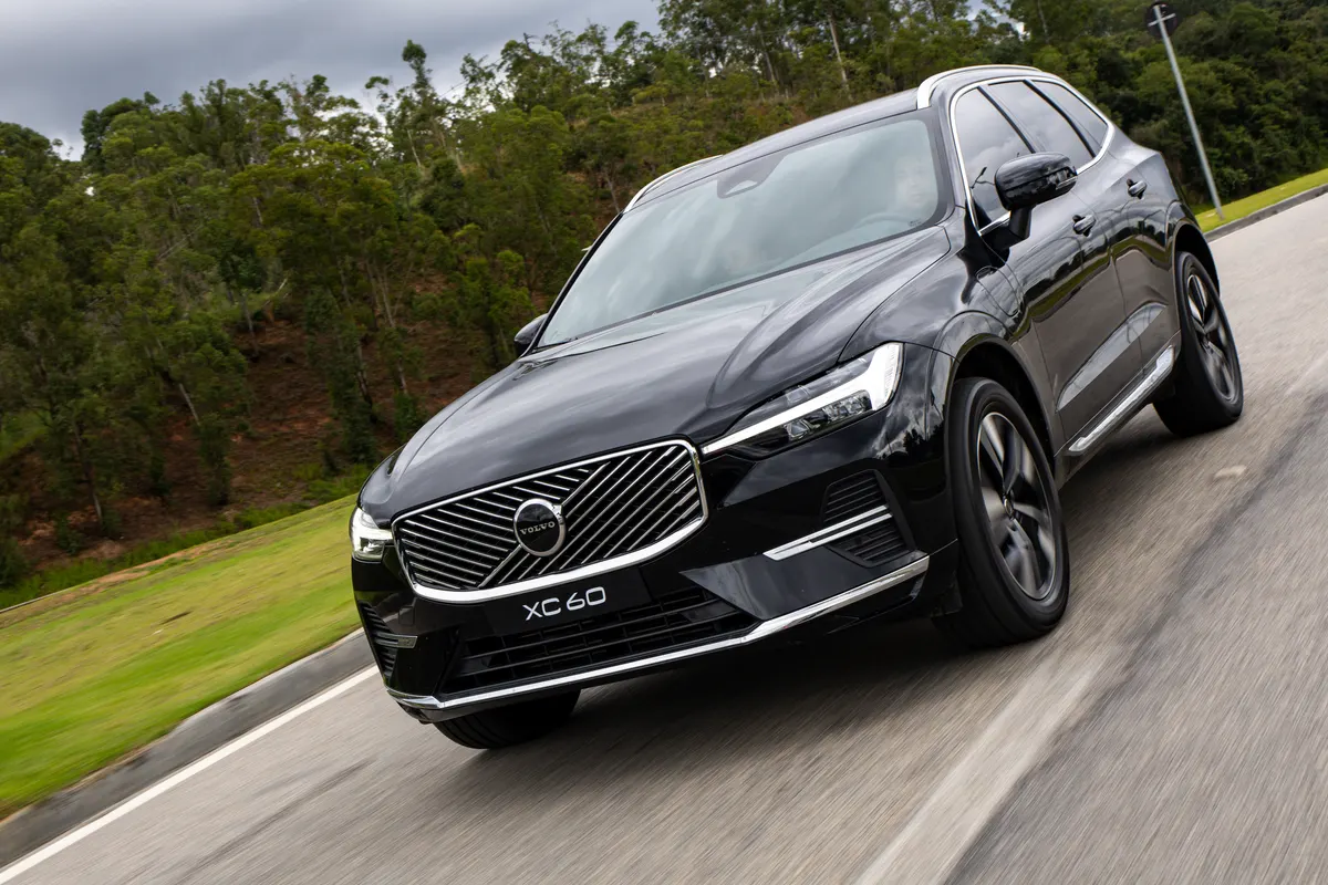 Volvo XC60 preto em movimento numa rodovia cercada de mata